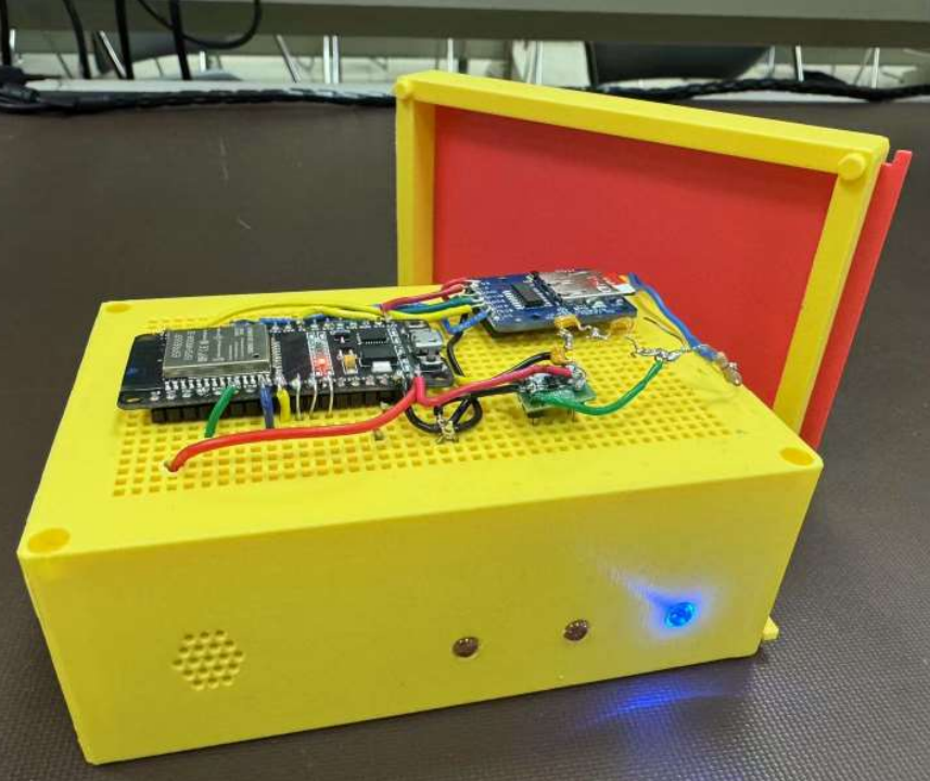 Close-up view of the WASM safety monitor device showing its ESP32 board, capacitive touch sensor, LEDs, and speaker.
